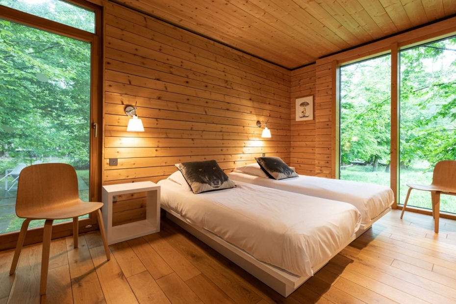 Deux lits simples dans une chambre en lambris avec deux grandes baies vitrées