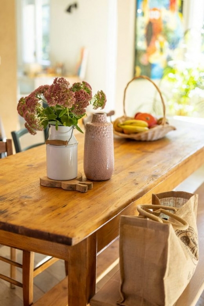 Table en bois recouverte de vases et d'un panier de fruits