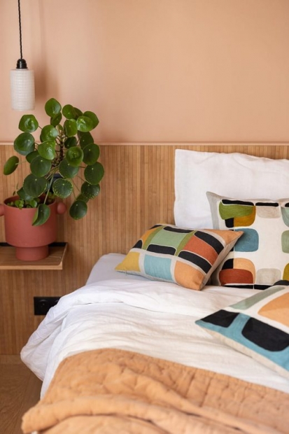 Zoom sur un lit et une table de nuit avec une plante verte