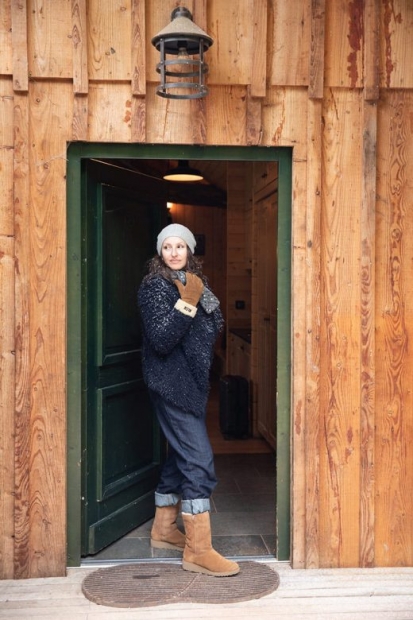 Femme chaudement vêtue devant la porte d'un chalet