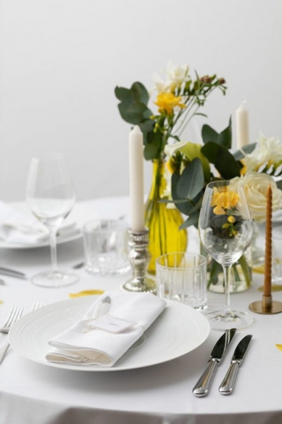 Zoom sur une assiette décorée d'une serviette blanche, à côté de laquelle se tient des vases